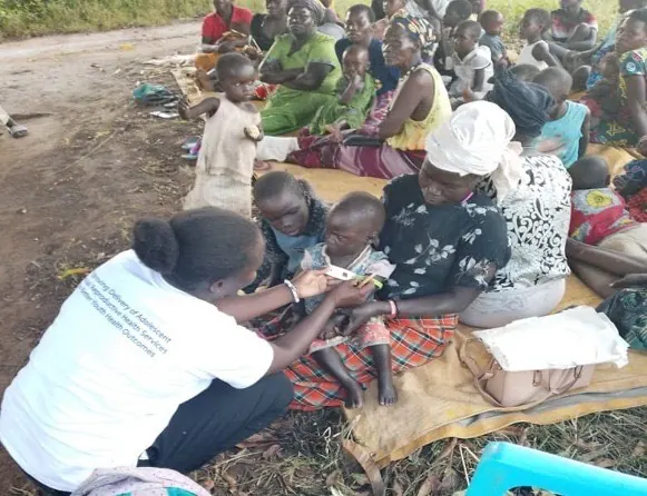 Child under MUAC malnutrition assessment by a health worker during community outreach